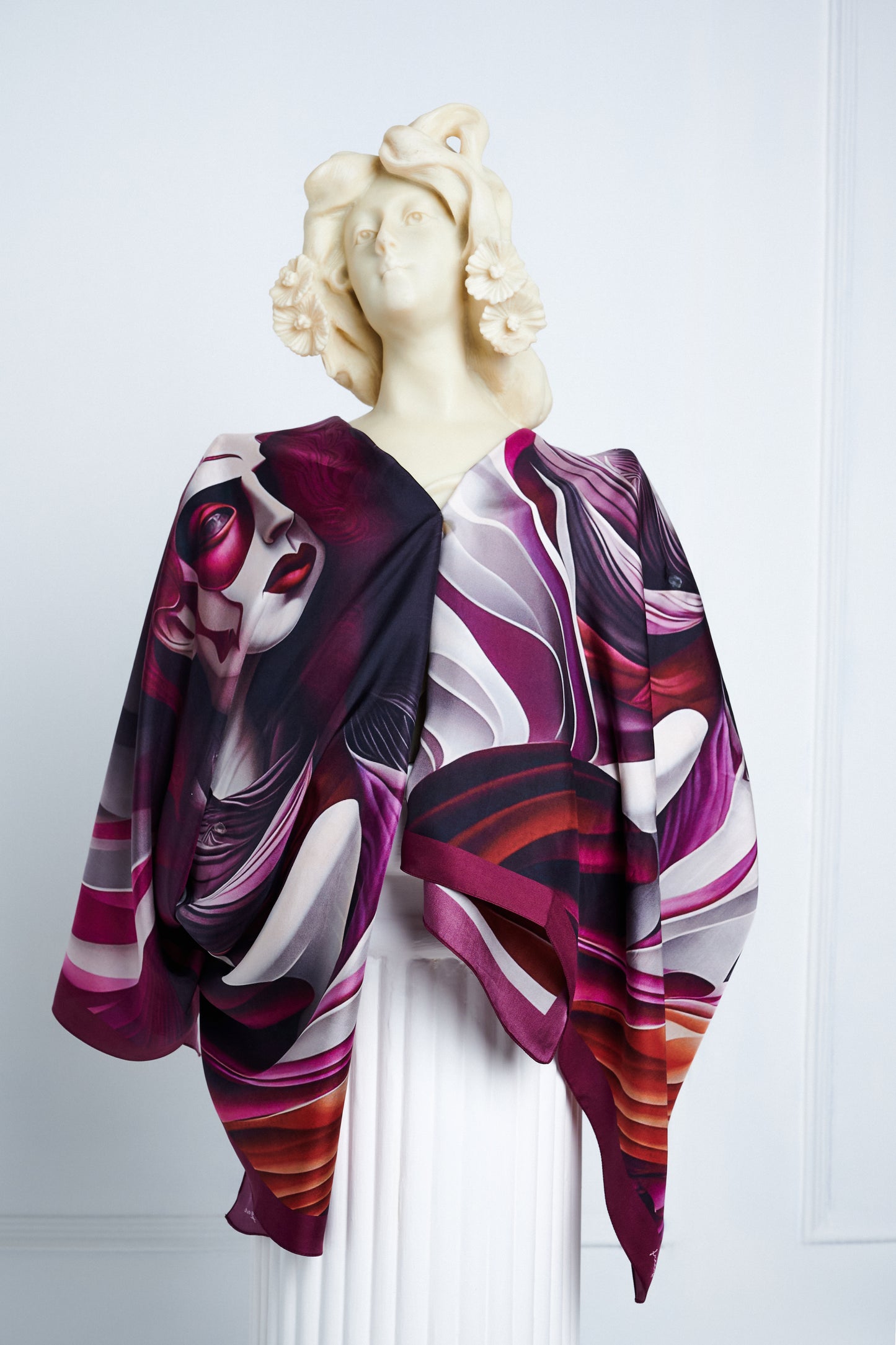 Écorché luxury scarf draped on a classical statue, showcasing its surrealist anatomical details in maroon and white.