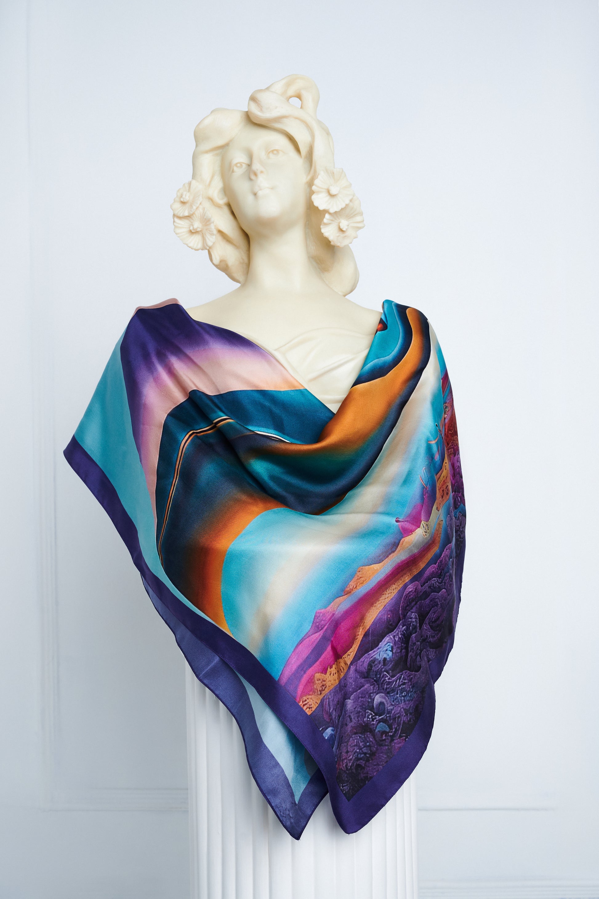 Epipháneia scarf draped on a classical statue, showcasing surrealist design elements.