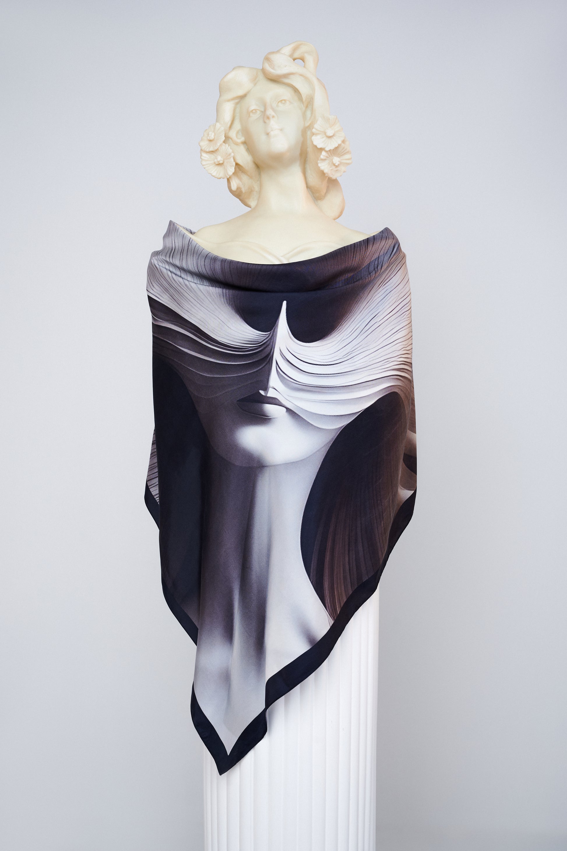 L'Esprit Fluctuant luxury scented scarf by Freeque draped on a sculpture, showcasing abstract artistry in black silk.