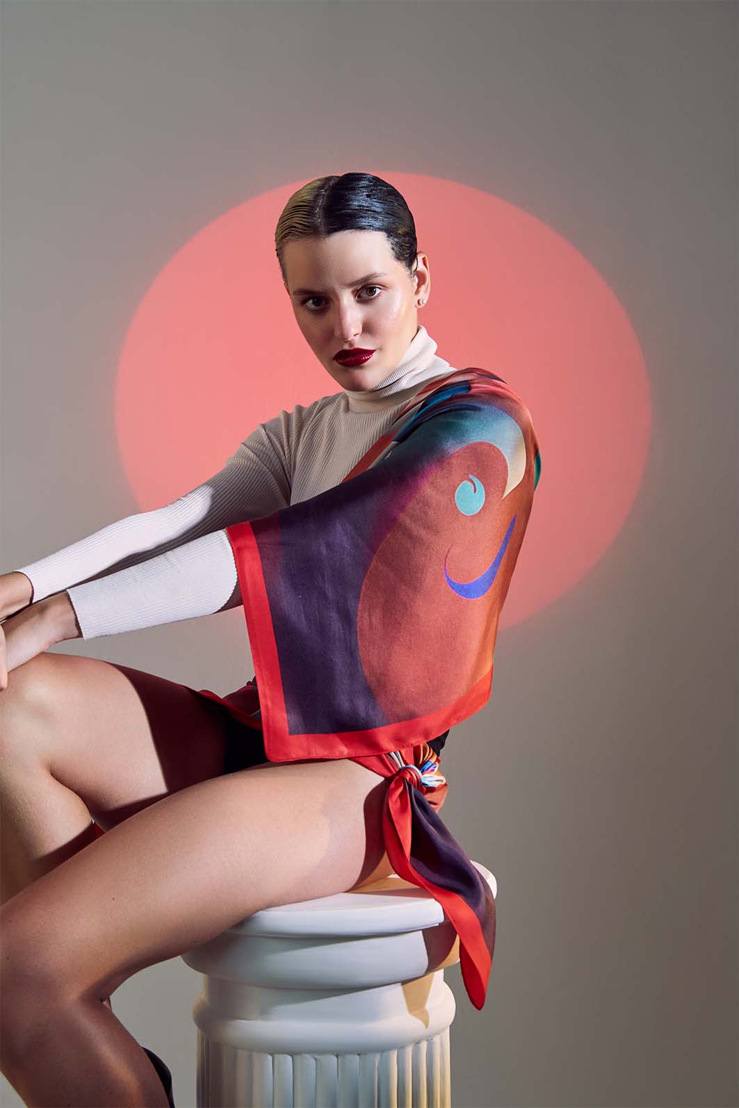 Close-up of model with Furor scented scarf draped over the shoulder, enhancing the visual impact of the red circular background.