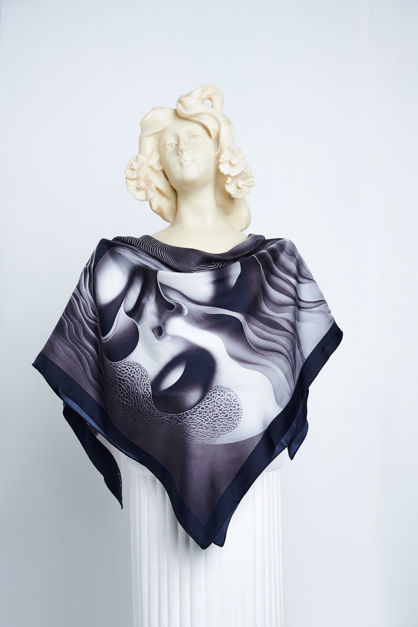 Apathia ‘Numb’ luxury scented scarf draped on a statue, depicting two faces in grayscale, inspired by emotional detachment.