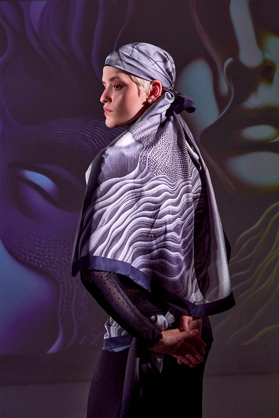 Model wearing Apathia ‘Numb’ scented scarf in grayscale, showcasing surreal art of two faces, from Freeque’s Hygieia Collection.
