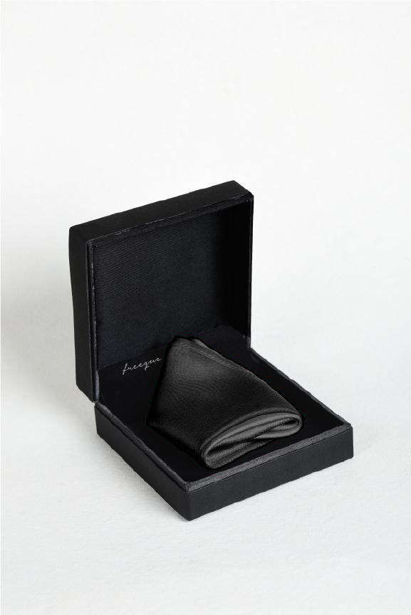 Solid charcoal satin silk pocket square displayed in a black box - fragrance-infused luxury accessory by Freeque.