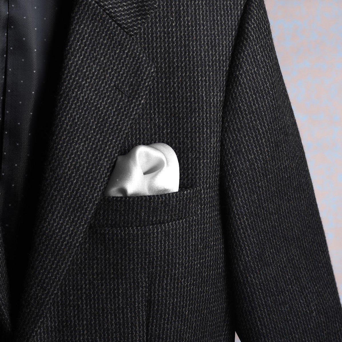 Solid white scented pocket square styled in a suit pocket - luxury accessory by Freeque.