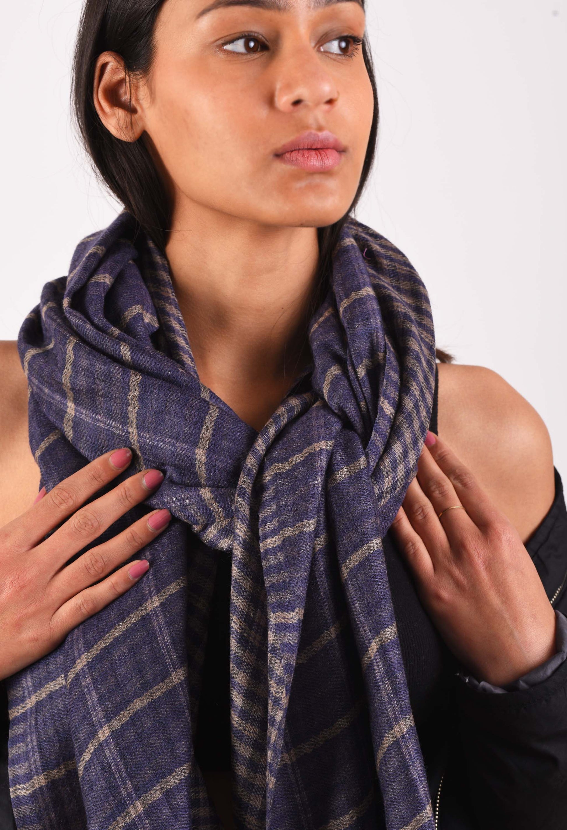 Close-up of Kai stole with checkered pattern in camel wool, wrapped around the model's shoulders.