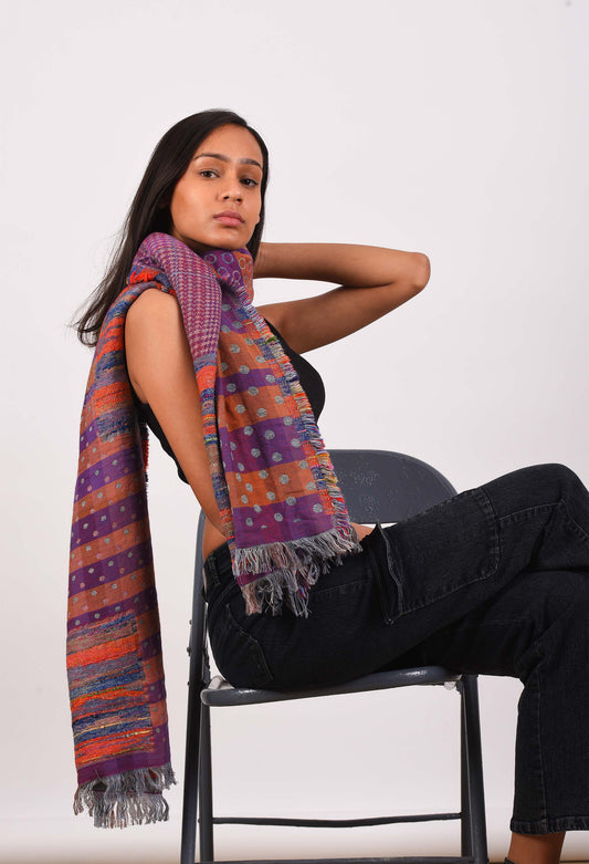 Model wearing luxurious camel wool stole in vibrant colors, styled over a chair