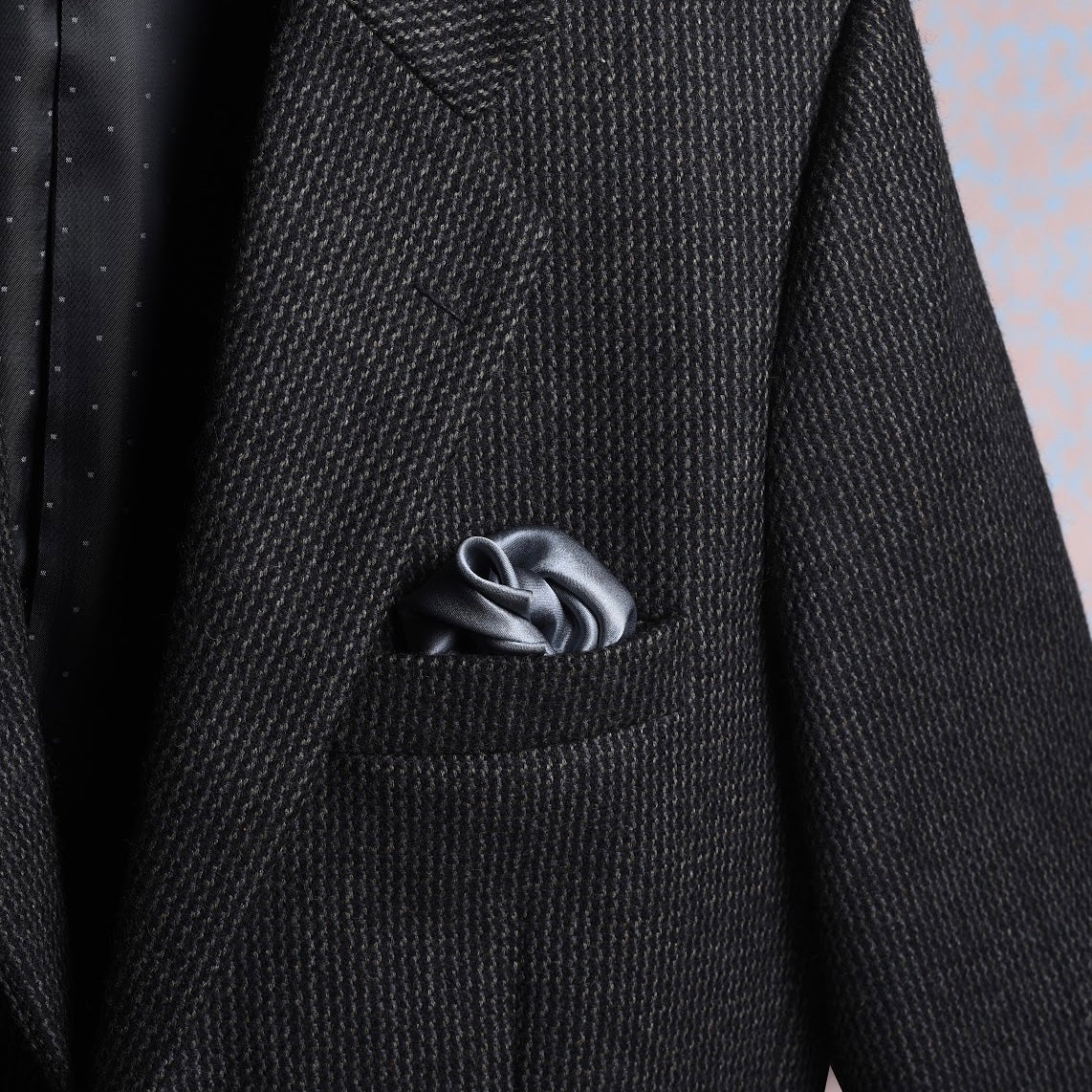 Solid grey satin silk scented pocket square in jacket pocket for a luxurious look.